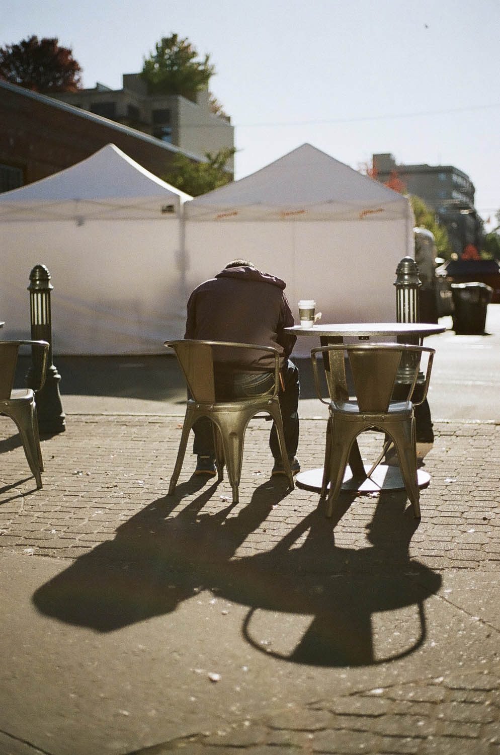 Lomography 400 ~ Canon AE-1 ~ Canon 50mm F1.8 Morning light bathes a man as he enjoys a coffee and a newspaper in downtown Bend, Oregon.